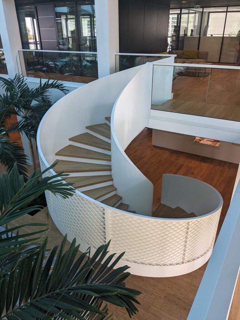 Escalier Colimaçon Design Blanc et Bois - Bureau Moderne Escalier en colimaçon blanc et bois dans un espace moderne avec plantes vertes.